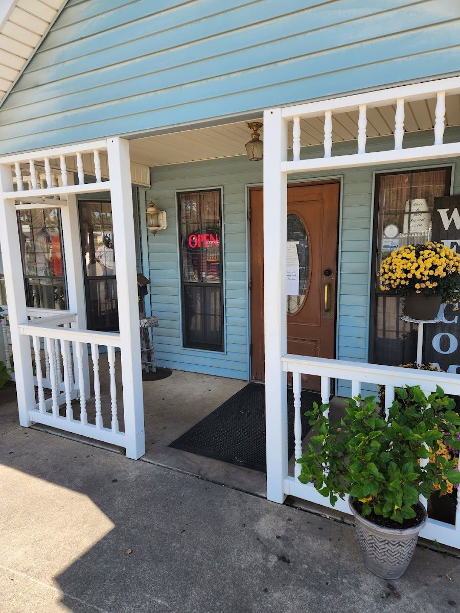 The front porch, with white railings, blue siding and potted mums